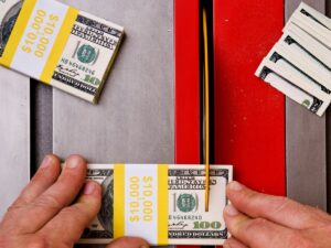 using a saw without a guard to cut a stack of 100 dollar bills to represent budget cuts